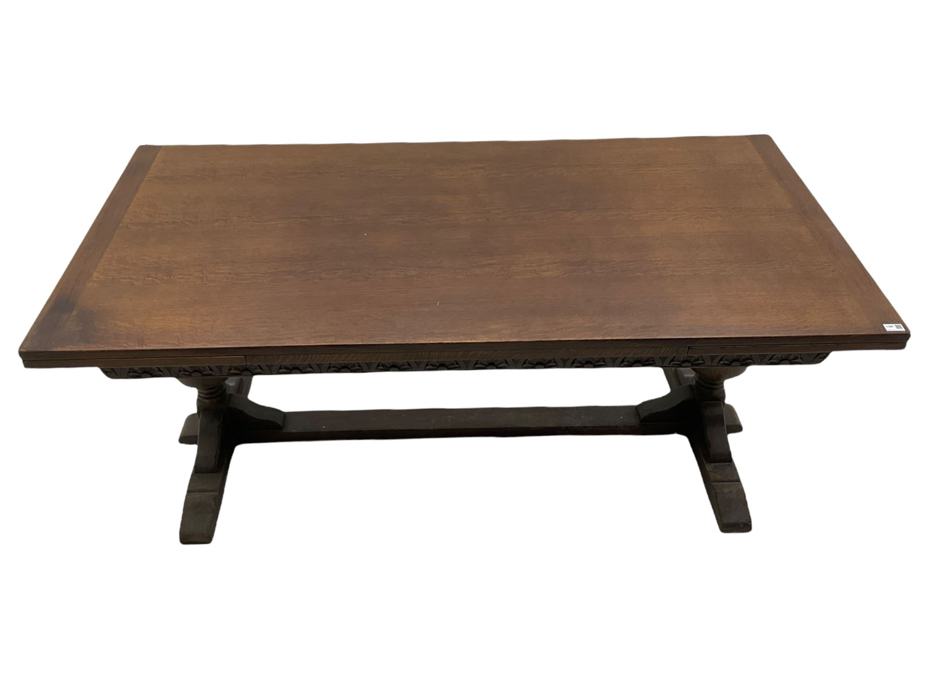 20th century oak drawer leaf extending dining table, two foliage carved baluster supports on sledge feet joined by floor stretcher 