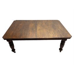 Edwardian oak extending dining table, rectangular moulded top with canted corners, three additional leaves and winder, flower head carved and turned supports with fluted decoration, on brass and ceramic castors