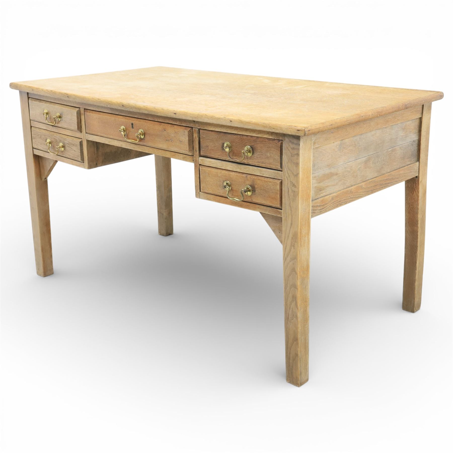 20th century oak kneehole desk, the rectangular top above central drawer and kneehole, flanked by short banks of two drawers, each fitted with brass drop handles, raised upon four plain slightly tapering legs, 75.5cm x 135cm x 73.5cm