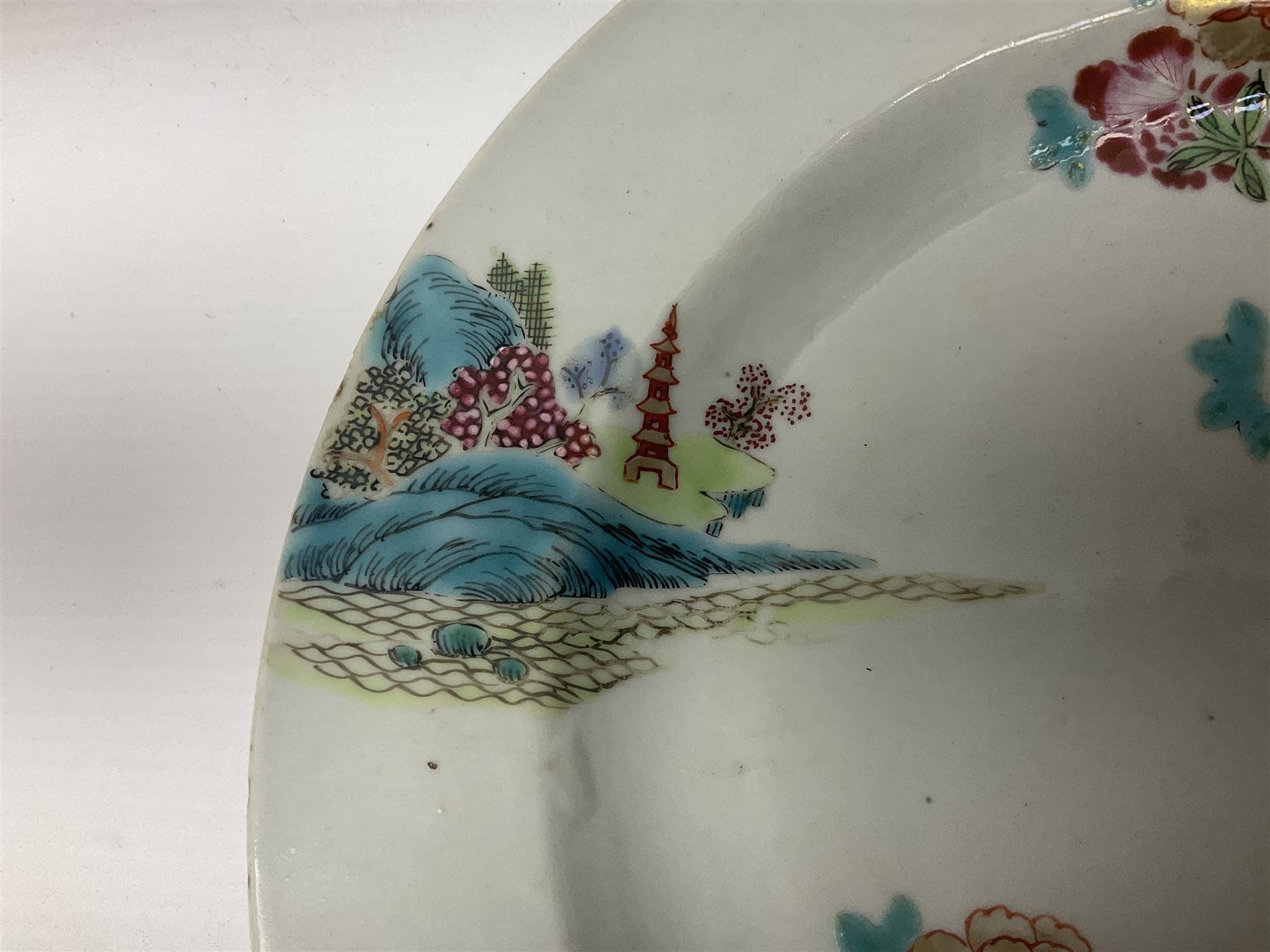 Three 18th century Chinese Famille Rose plates, the first example enamelled with blossoming peonies, rockwork and fence, the other two examples of similar design, decorated with blossoming peonies and sprigs within shaped inner borders, each approximately D23cm