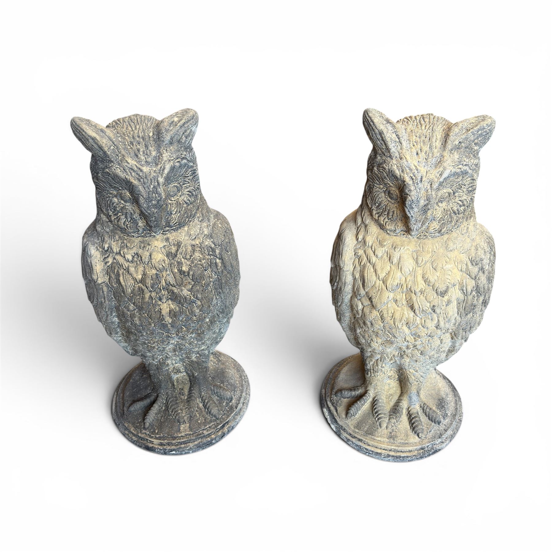 Pair of large composite stone garden statues modelled as standing horned owls, raised on circular bases