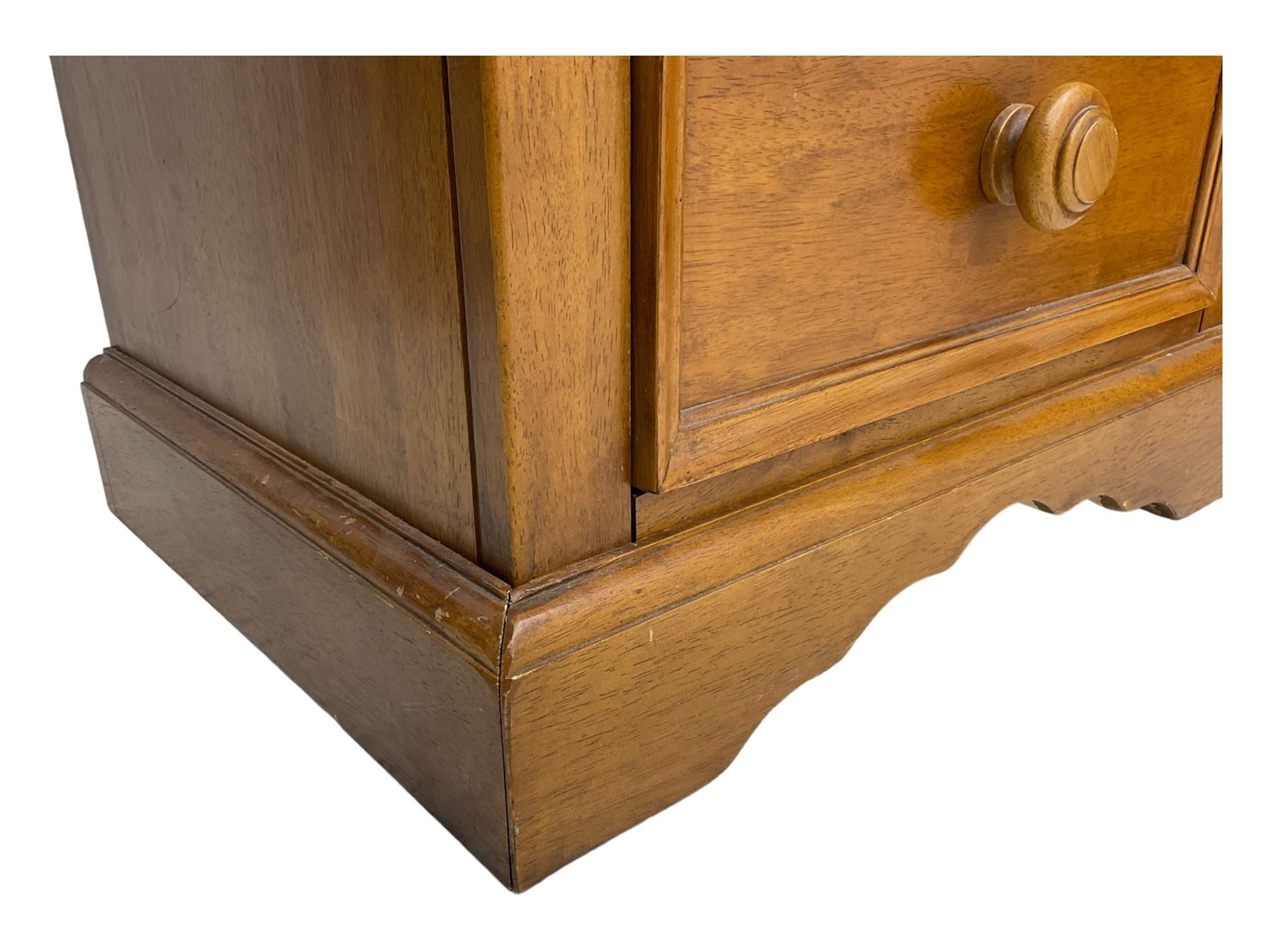 Pair of contemporary cherry wood bedside chests, rectangular top and projecting moulded cornice over three drawers, on plinth base with shaped apron