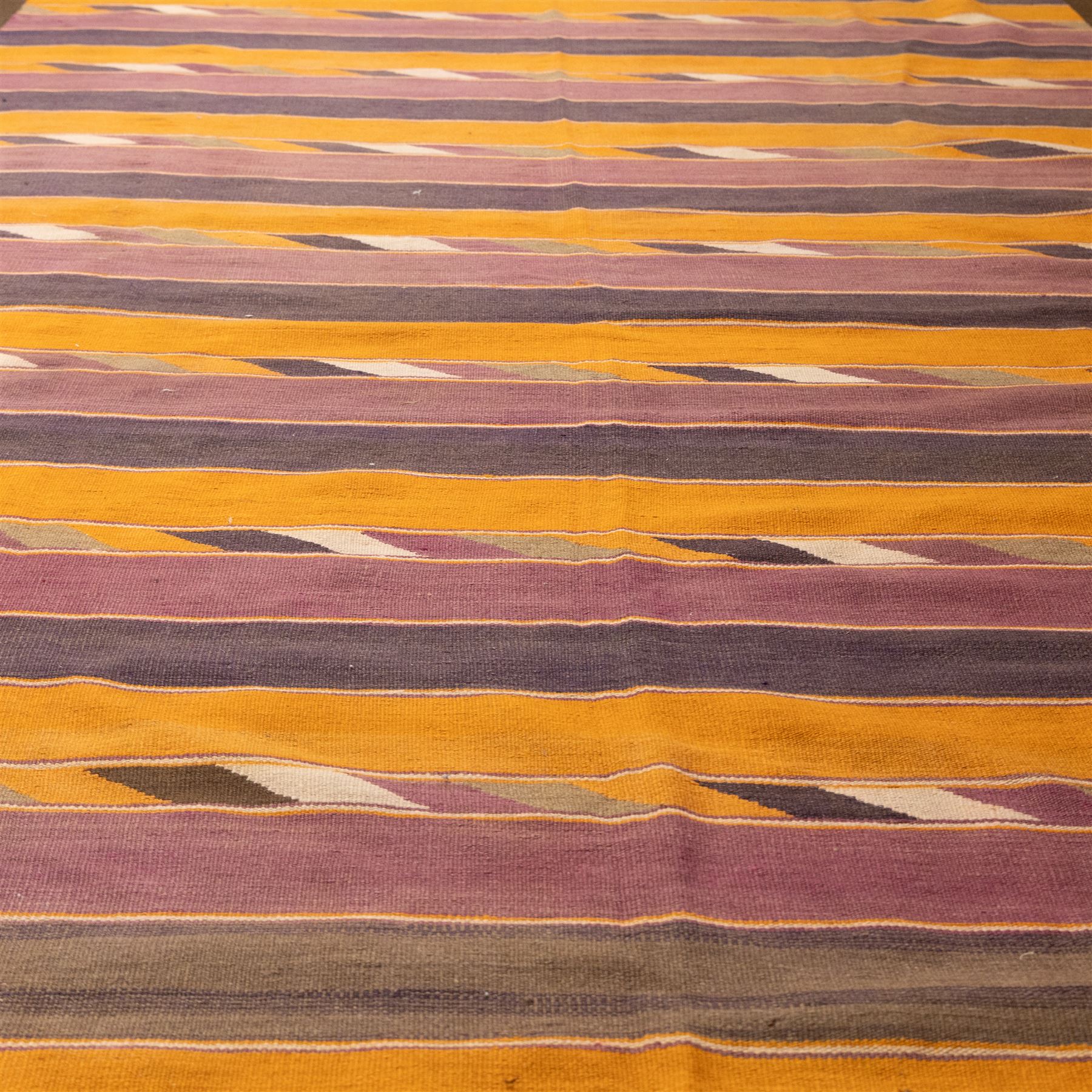 South West Persian Qashqai flatweave kilim, field decorated with bold horizontal bands in shades of aubergine, plum and orange, ochre, olive and lilac, interspersed with narrow registers of diagonal chevron motifs in cream and dark brown, framed by brown end panels, with fringe ends 