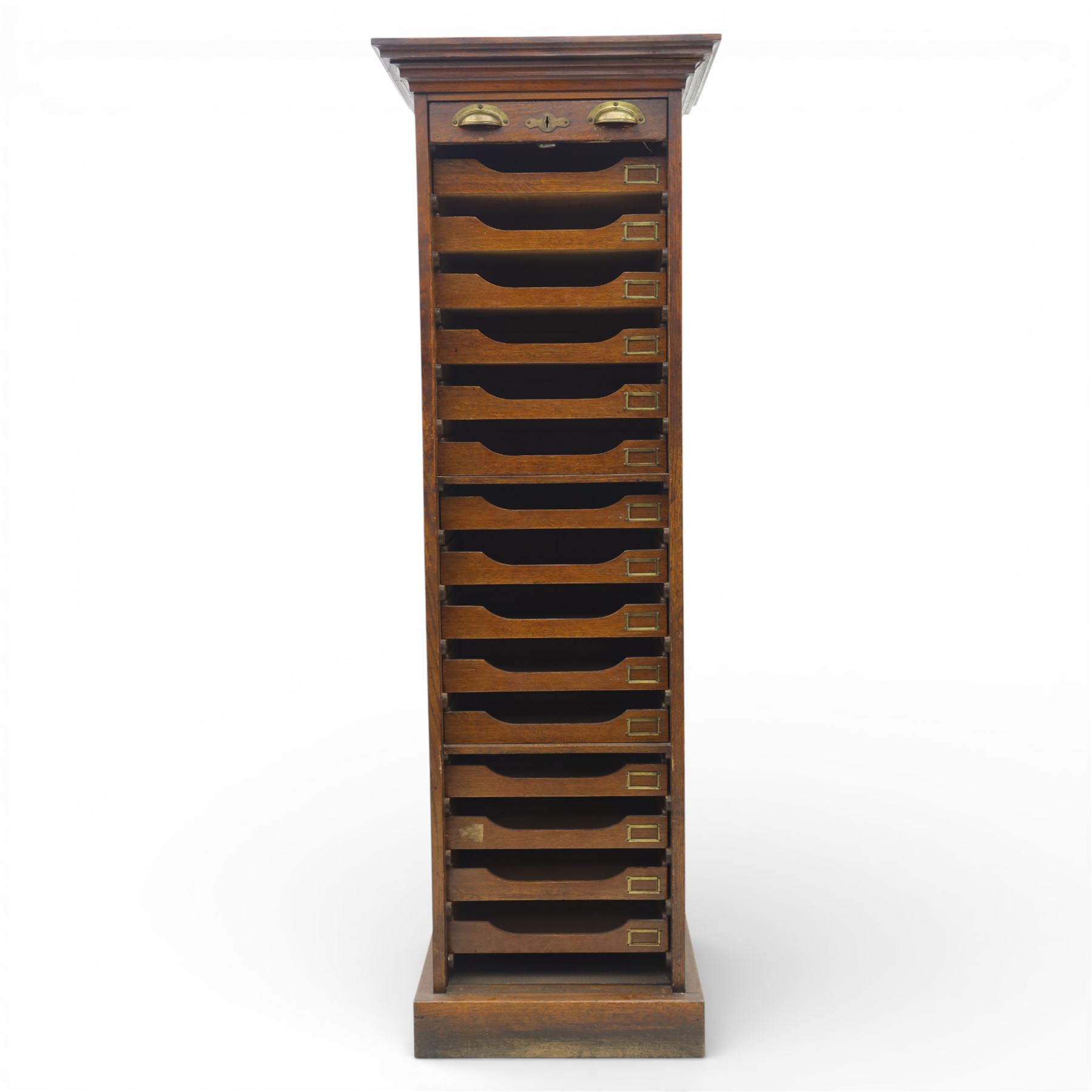 Edwardian oak pedestal office cabinet, moulded rectangular top over tambour shutter enclosing fitted interior, with fifteen graduated drawers each with recessed brass cup handle and label holders, panelled sides, on plinth base