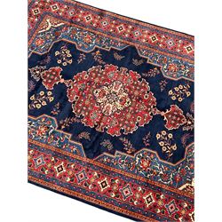 Persian Veis indigo ground carpet, the field with large pole medallion decorated with Herati motifs and surrounded by floral sprays, crimson ground border with repeating cross motifs and stylised flower heads, within guard stripes 