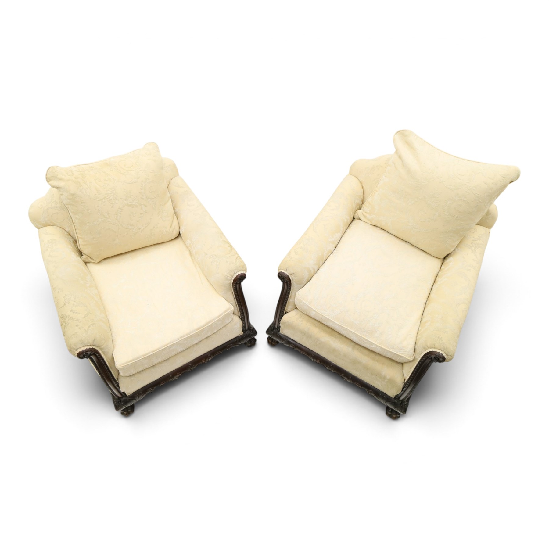 Quality Edwardian carved mahogany lounge suite comprising three-seater settee and pair of armchairs, the sofa with arched back over rolled arms and deep sprung seat, the arm terminals carved with acanthus rosette over gadroon and rope-twist moulding, the shaped apron carved and moulded with scrolling foliate acanthus motifs, terminating to four large front hairy paw and ball feet, upholstered in pale yellow foliate fabric with matching seat and scatter cushions (W200cm D105cm H73cm); the matching deep armchairs (W78cm D95cm H75cm)