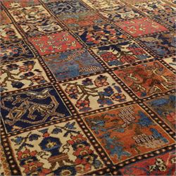 Central Persian Bakhtiari Kheshti design hand-knotted rug, field composed of a grid of square panels, each containing stylized floral devices, animal and foliate motifs woven in a rich palette of madder red, indigo blue, ivory ochre and brown, framed by a multiple striped border with a meandering vine and flowerhead band, with cotton fringe ends 