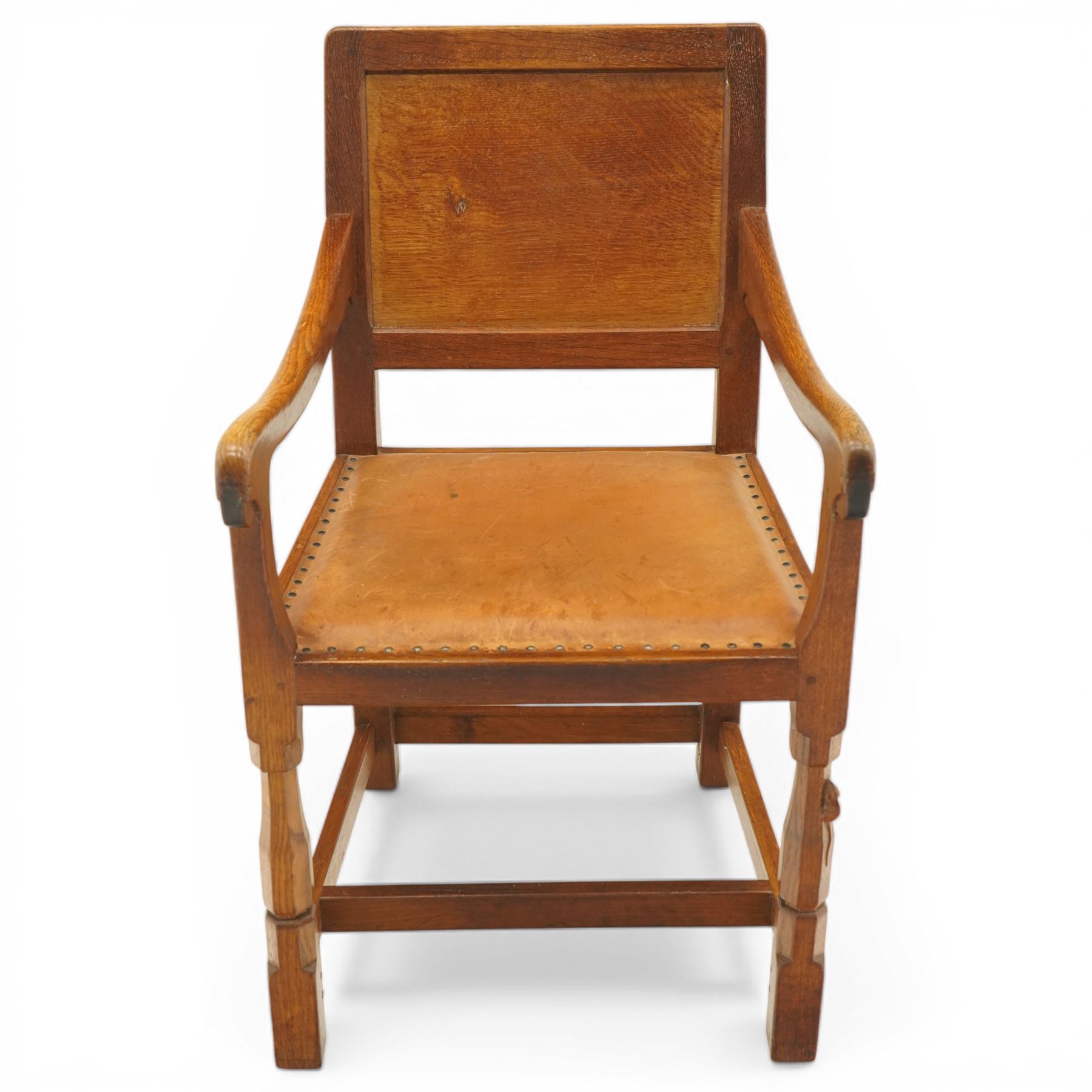 Mouseman - oak panel back carver armchair, lightly adzed panel back above a tan seat with brass studded trim, flanked by swept arms raised on octagonal front supports, with carved mouse signature, by the workshop of Robert Thompson of Kilburn