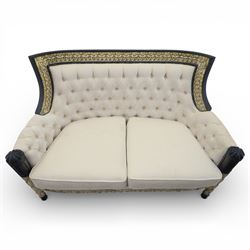 20th century Louis XVI style settee, upholstered in cream fabric with buttoned back and arms, and plain seat cushions, the shaped and black painted frame with entwined foliate detail and gilt flower heads, upon column legs with bun feet
