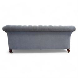 Early 20th century Chesterfield drop-arm two-seat settee, traditional shape with rolled arms and back, upholstered in buttoned pale blue fabric, on ogee block feet with brass castors 