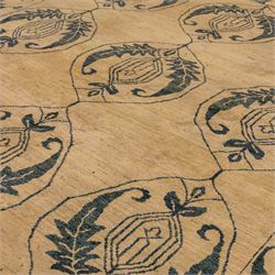 Late 20th century Turkish hand-woven carpet, golden beige field decorated with a repeating lattice of stylized medallions enclosing boteh and angular foliate motifs linked by issuing scrolling vinery within a border of complementary stylized leaf scrolls