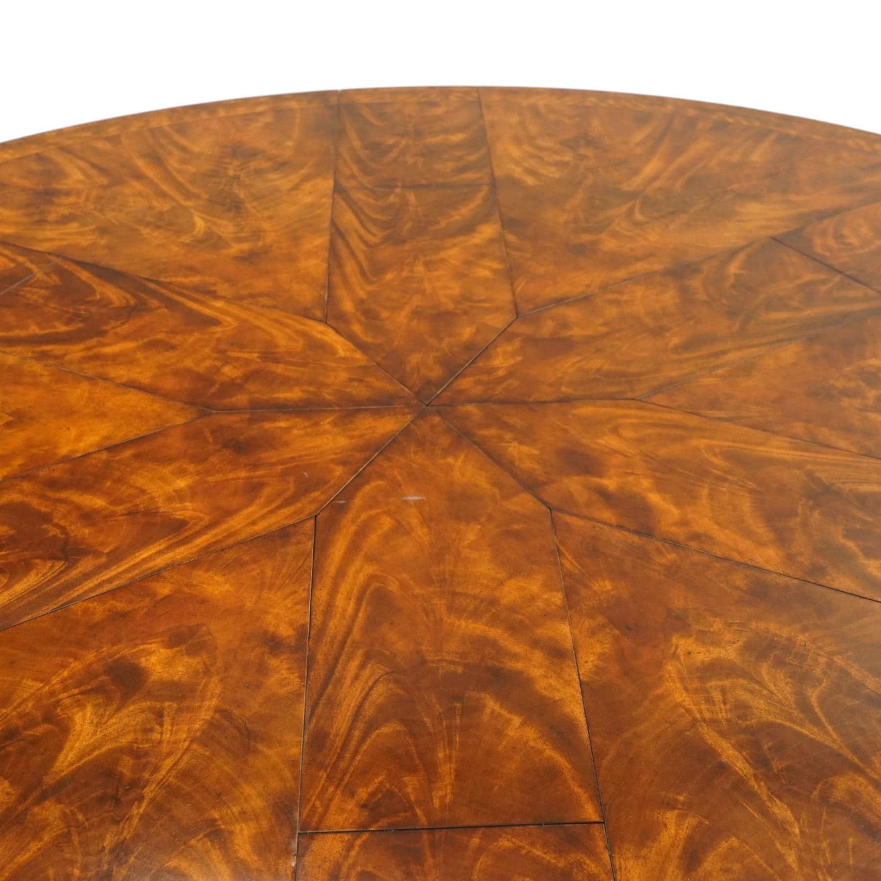 Theodore Alexander - Regency Revival figured mahogany 'Althorp Patent Jupe' extending dining table, the segmented circular top formed of six pull-out triangular divisions with inset fold-out leaves, raised on a large turned vasiform pedestal on a pentagonal platform base with ebonised stringing, terminating to five splayed supports with gilt metal acanthus scrolled feet, retailed by David Hick Interiors, Jersey