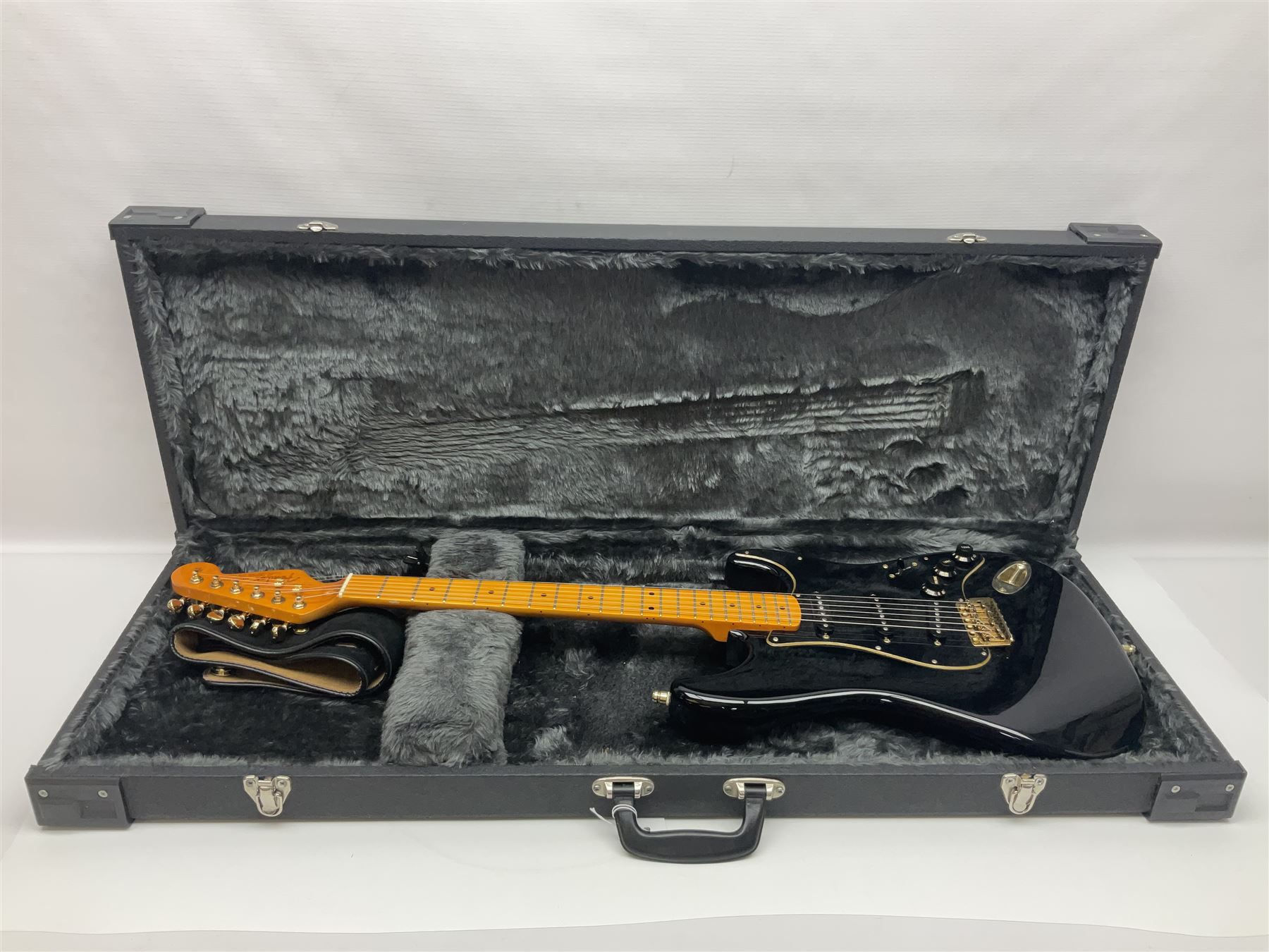 Copy of a Fender Stratocaster electric guitar in black with Wilkinson bridge, lock-in tuners, synchronised tremolo and various patent numbers; L99cm; in hard carrying case with strap and digital tuner
