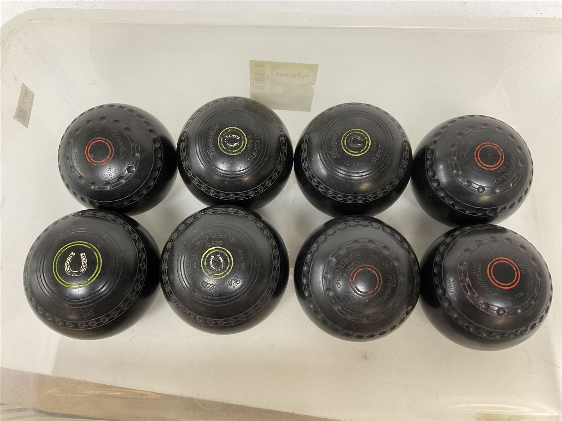 Eight lawn green bowling balls, comprising Helmselite Super-Grip sizes 2 and 5, in two sets of four