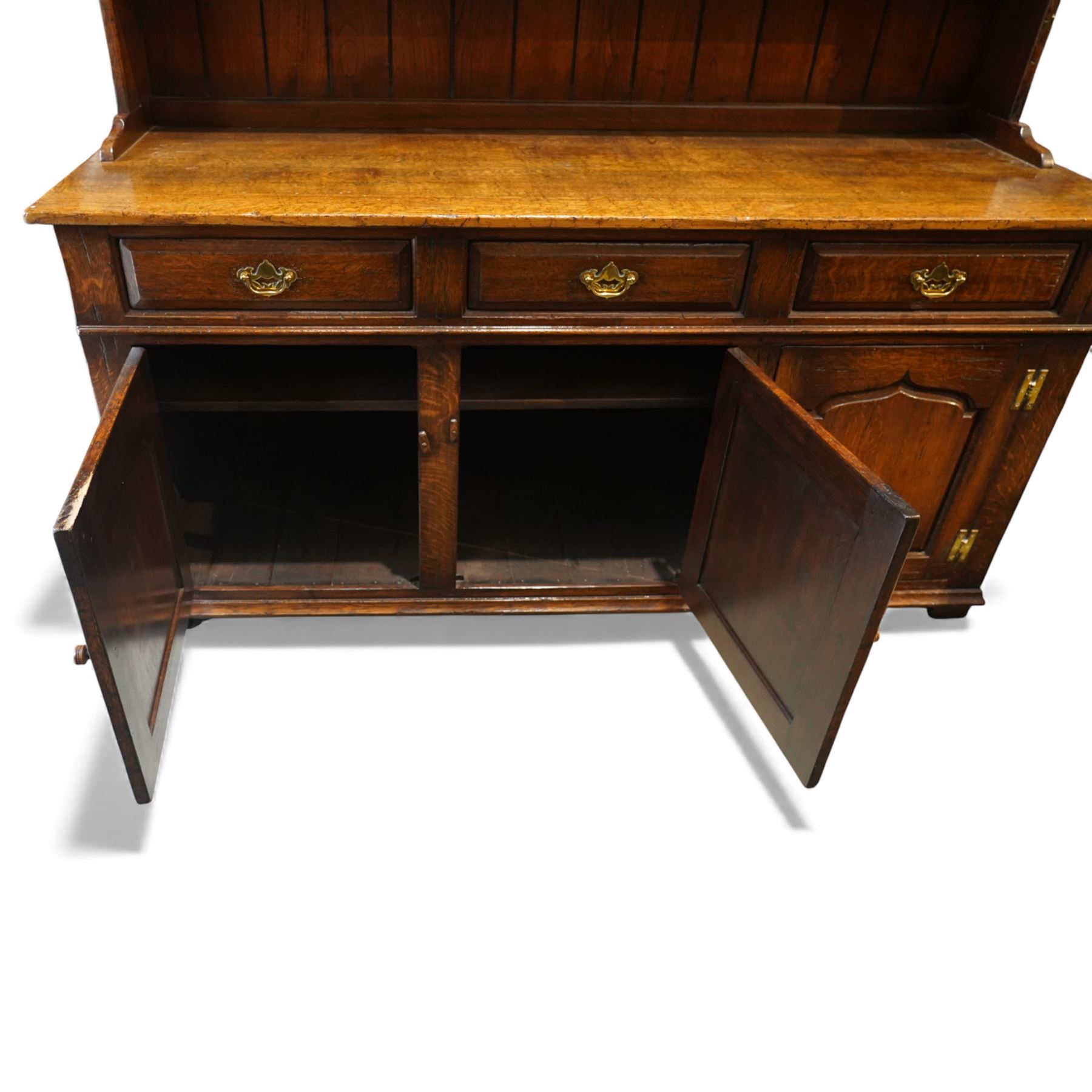 17th century style oak dresser, in the manner of Titchmarsh & Goodwin, fitted with a moulded top over three drawers and cupboard doors, the superstructure formed as a two tier panelled plate rack with integral trinket drawers