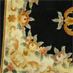 Chinese Aubusson design wool rug, black field with a central oval floral medallion framed by a wide border of scrolling flowers and foliage in soft pastel tones, with ivory spandrels and cotton fringe ends 