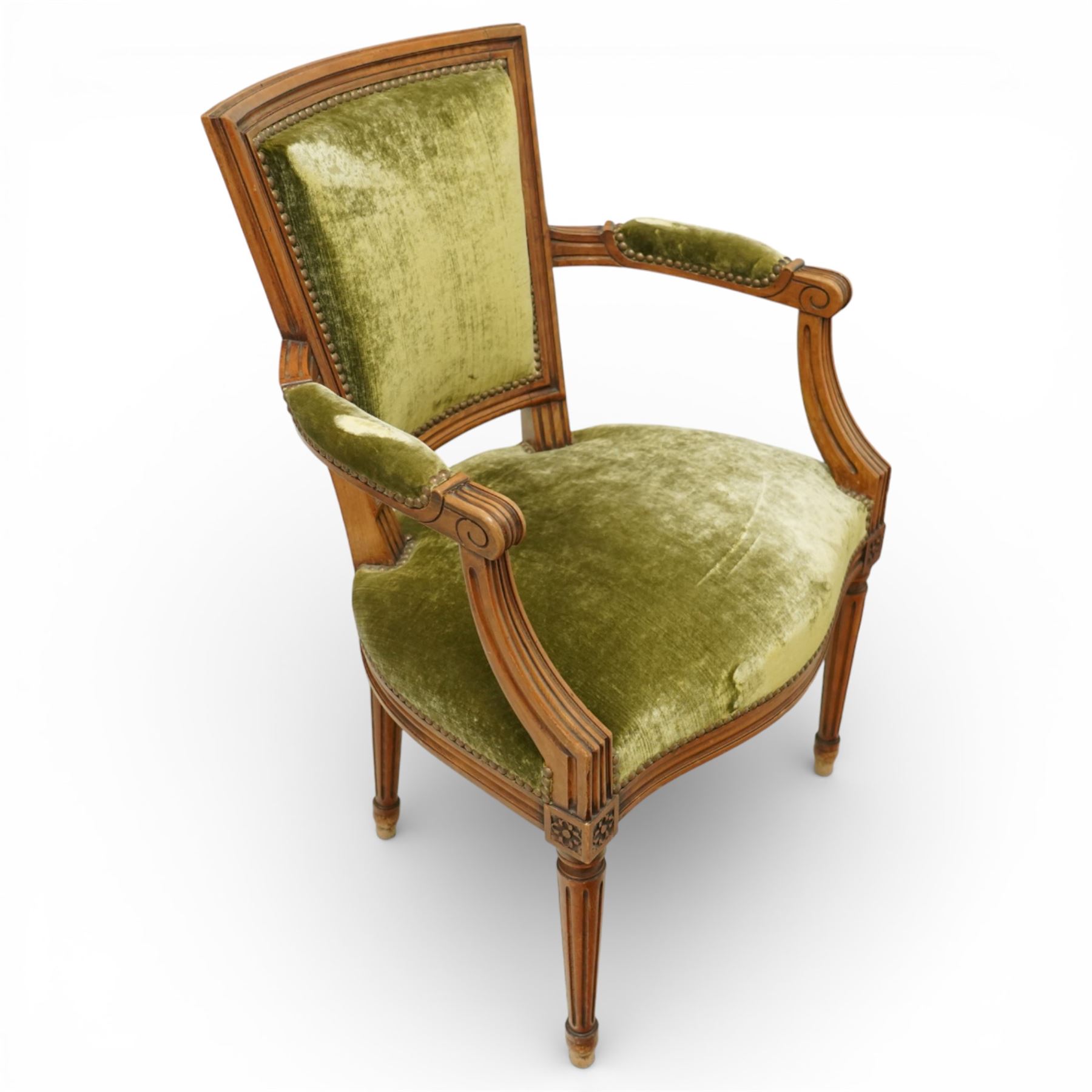 French Louis XVI style walnut armchairs, rectangular upholstered backs with nailhead trim, padded seats upholstered en suite, out-swept arms with upholstered pads, fluted supports with carved rosettes to the knees, on turned and fluted tapering legs