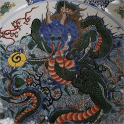 20th century Chinese charger, decorated in blue, green and red enamels with a four clawed dragon chasing the flaming pearl amidst waves and flower heads, the rim with border of alternating reserves of auspicious emblems and flower scrolls, bearing apocryphal Kangxi mark beneath, D38cm 

