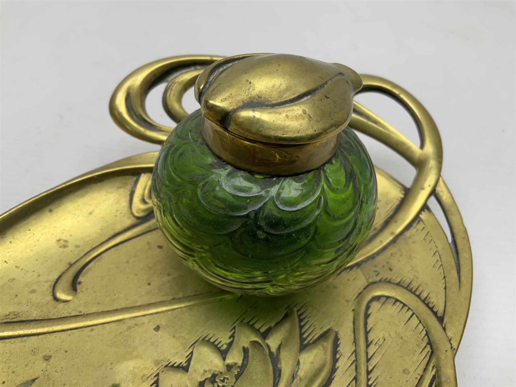 Art Nouveau Geschutzt brass desk stand, with stylised whiplash relief decoration, with removable Loetz style green glass inkwell, stamped to the base, H8cm