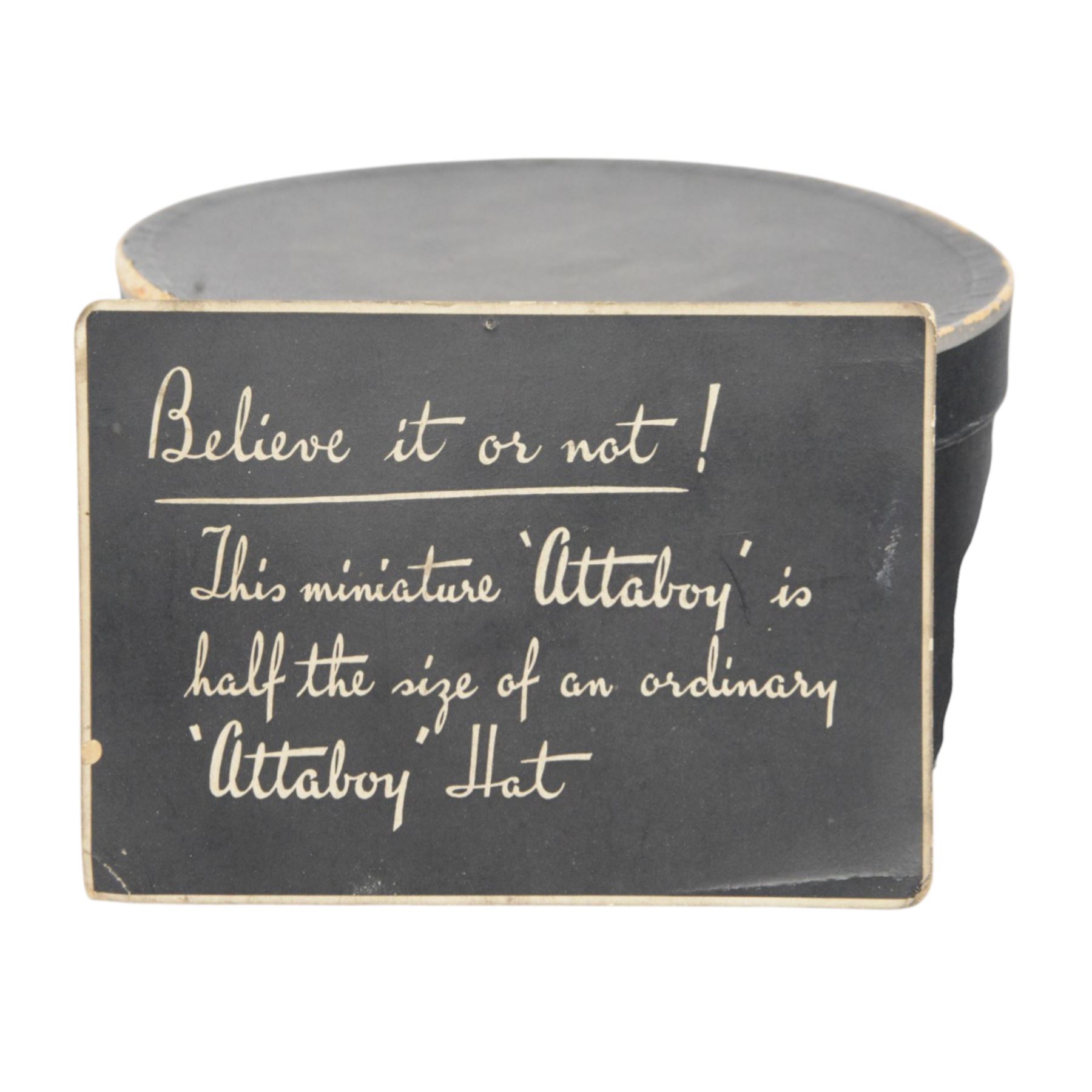 Two Attaboy tradesman or miniature trilbies, in black miniature hat boxes, one with a certificate 'Believe it or not! this miniature 'Attaboy' is half the size of an ordinary 'Attaboy' hat' together with a miniature flat cap, trilby H7cm     