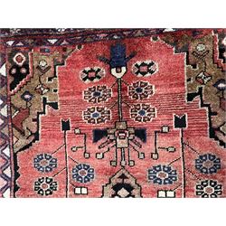 Persian Hamadan rug, the red ground field decorated with triple medallions and stylised flower heads, repeating geometric design border with guards