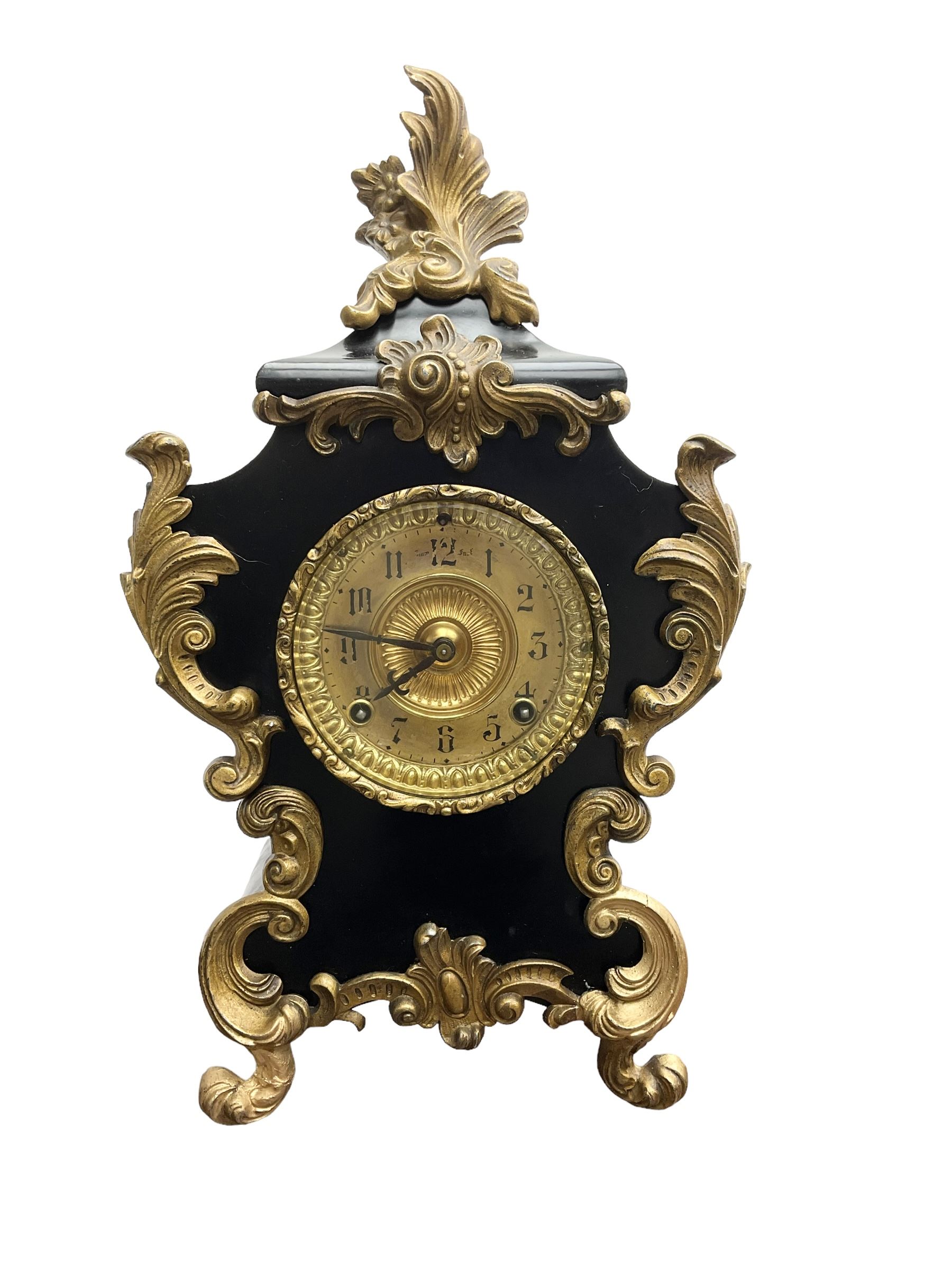Ansonia - American late 19th century steel cased 8-day mantle clock in a Rococo case with decorative brass mounts, brass dial with Arabic numerals, steel hands and a repousse dial centre, twin train striking movement sounding the hours and half hours on a gong. with pendulum and key.