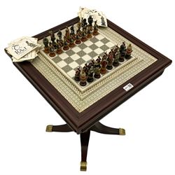Franklin Mint Indian ' The Raj ' chess set with marble effect chess board within a mahogany stained frame raised on a brass mounted pedestal base with single fitted drawer, the playing pieces depicting figures from the 1857 Raj mutiny 52cm square H68cm