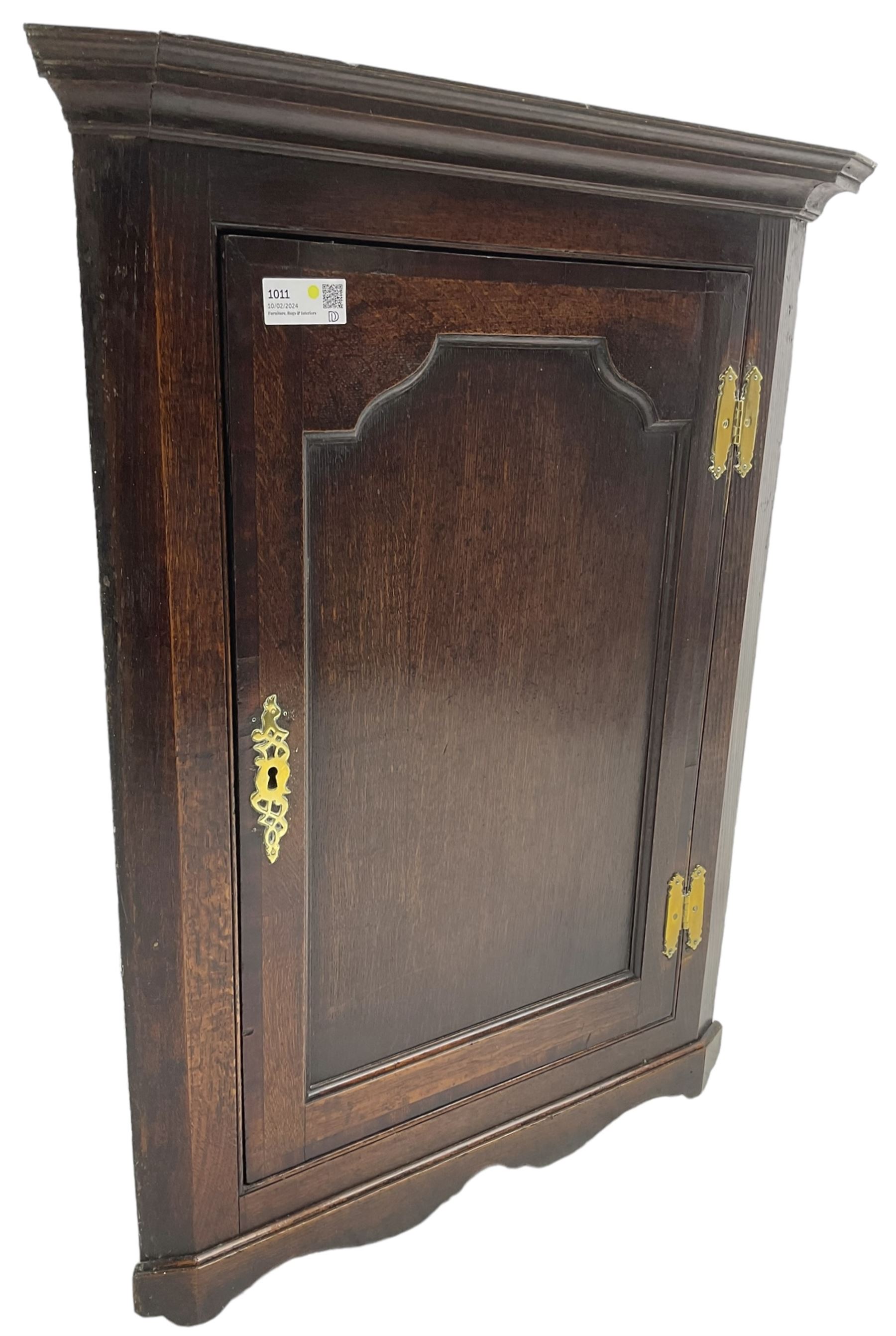 George III oak wall hanging corner cupboard, projected cornice over crossbanded and fielded panelled door, enclosing three shelves
