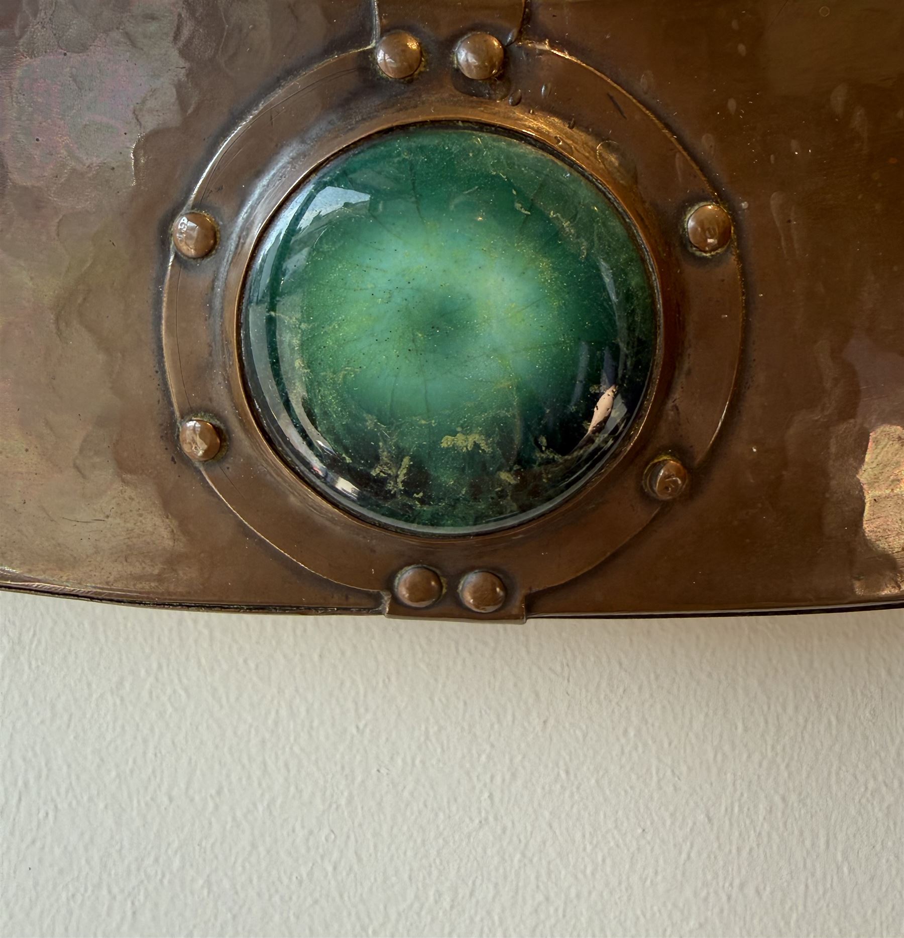 Liberty & Co, Arts and Crafts hammered copper framed oval wall mirror, mounted by four turquoise Ruskin cabochon roundels, with ivorine maker's label verso
