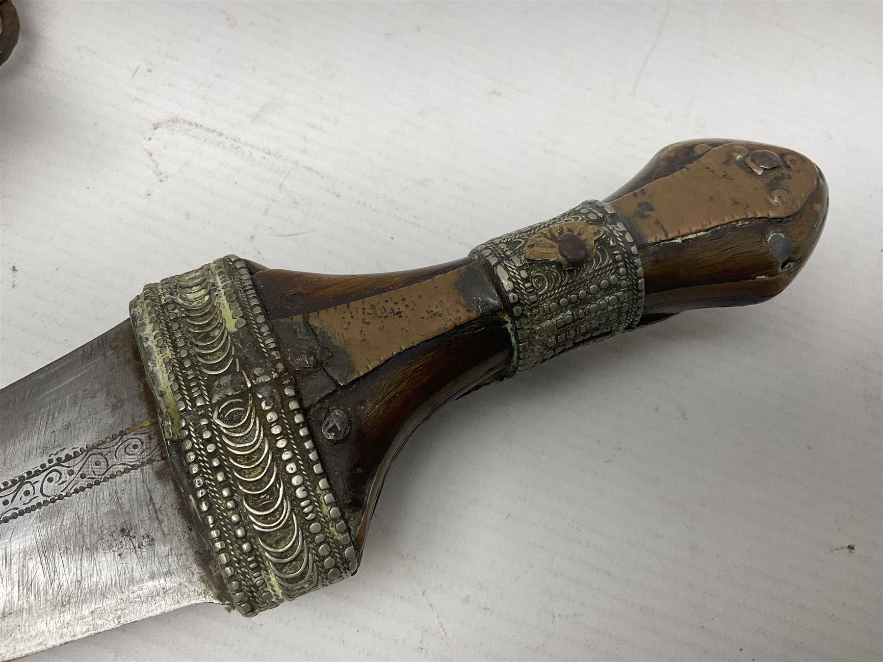 Saudi Arabian khanjar dagger with 29.5cm curving double edged  steel blade; white metal and copper mounted horn grip; in white metal mounted brass and leather scabbard incorporating embroidered leather wearing strap