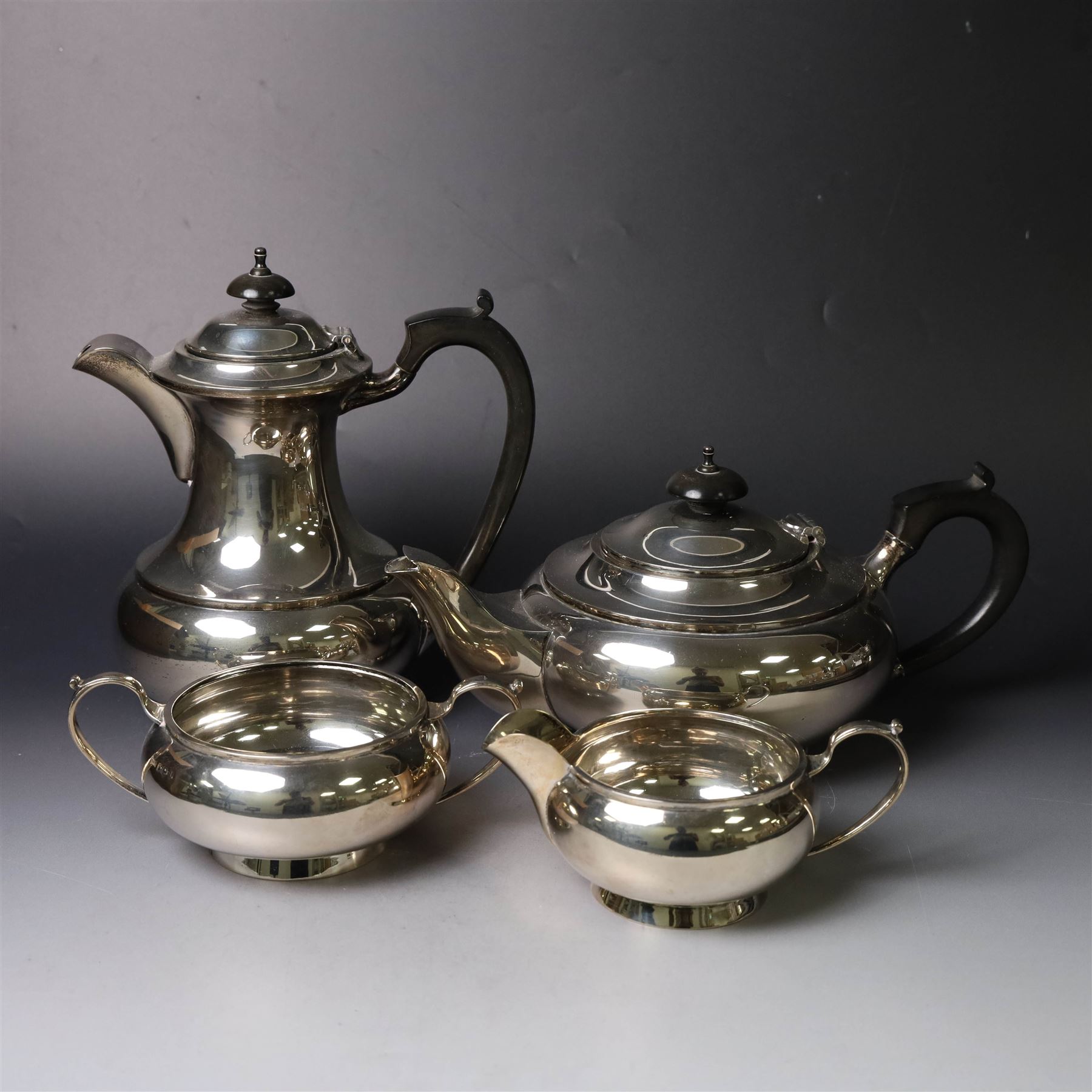 Mid 20th century silver four piece tea service, comprising teapot, hot water pot, open sucrier and milk jug, all of squat bellied form, the teapot and hot water pot with ebonised handles and finials, hallmarked Walker & Hall, Sheffield 1953, hot water pot H19cm