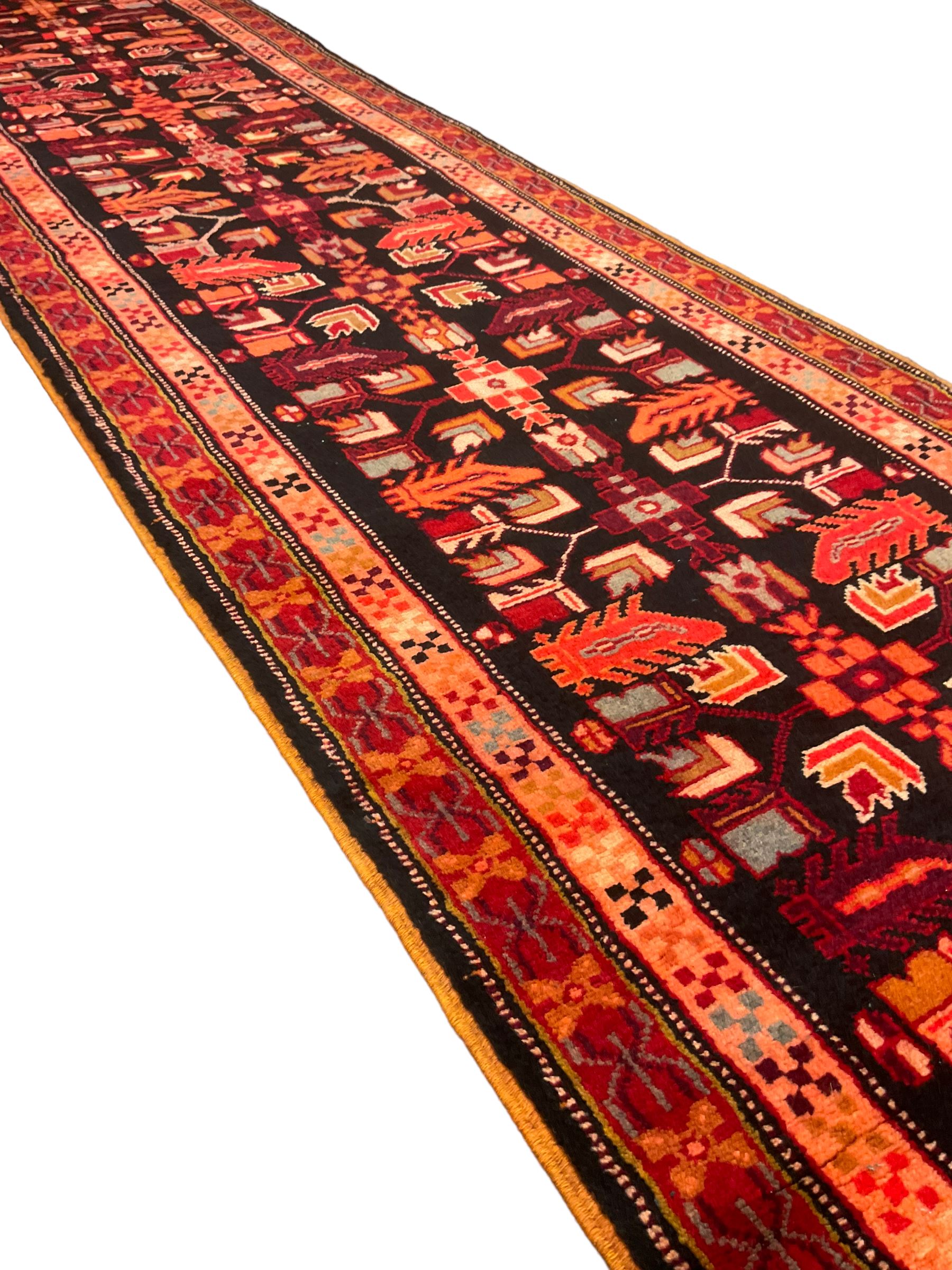 North West Persian Heriz runner, dark indigo ground field decorated with Herati motifs, peach and red borders with geometric design 