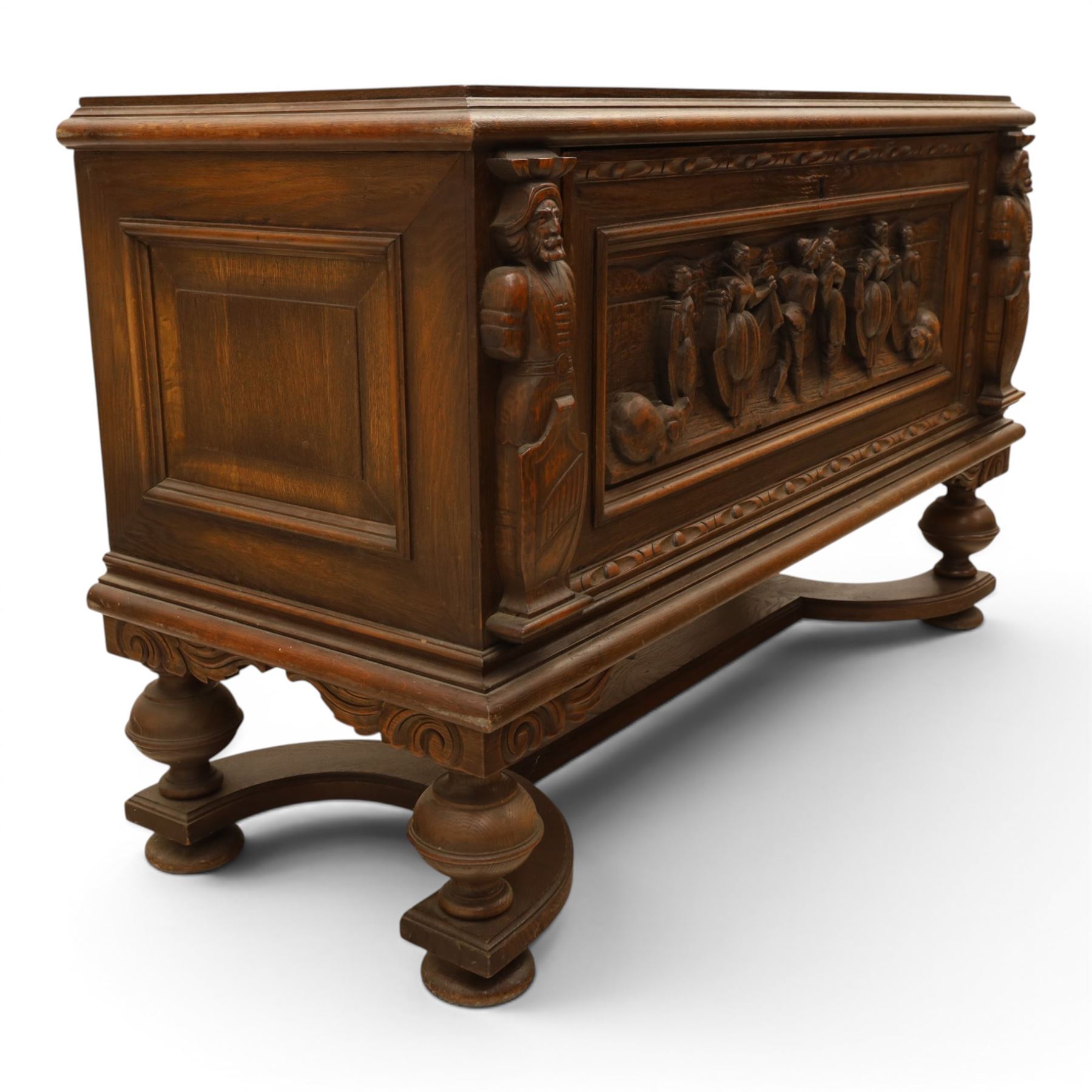 Carved oak coffer bench, rectangular moulded top above carved fall front, with figural, mask and foliate decoration, panelled sides, raised on turned bun feet with shaped lower apron