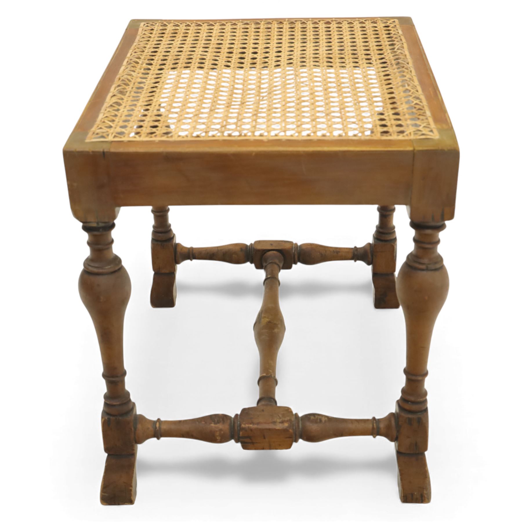 Two upholstered and caned footstools, a late Victorian carved mahogany footstool, oval form upholstered in geometric kilim-style fabric, on cabriole supports (H 27cm, W 56cm, D 47cm), together with a 20th century beech stool, square caned seat on turned supports united by stretchers (H 43cm, W 44cm, D 37cm)