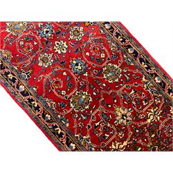 Central Persian Kashan crimson ground runner rug, the field decorated with interlacing branch and stylised flower head motifs, the guarded indigo border with repeating trailing foliate patterns