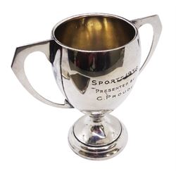 1930's silver trophy cup, of typical form, with twin angular and curved handles, the bowl with presentation engraving, upon a short pedestal foot, hallmarked J A Wylie & Co, Birmingham 1932, together with two early 20th century cigarette cases, the first example with engine turned decoration and engraved monogram to panel of upper left corner, hallmarked Morgan & Boon, Birmingham 1931, the second of plain form with engraved monogram, Charles S Green & Co Ltd, hallmarked 1916, approximate total weight 9.37 ozt (291.5 grams)