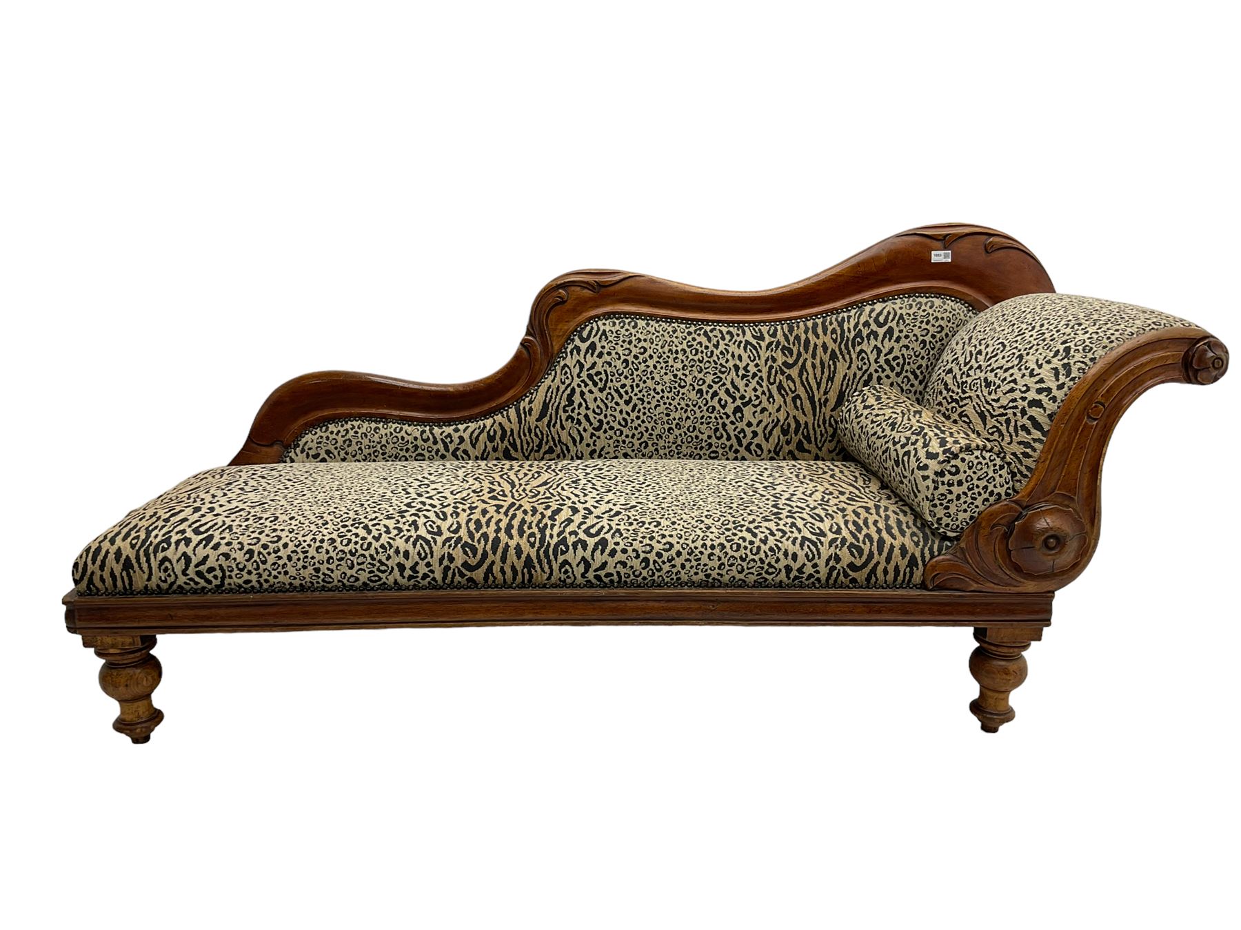 Victorian mahogany framed chaise longue, shaped arm carved with acanthus leaves, the scrolled back with applied carved rosettes,upholstered in monochrome leopard print fabric with bolster cushion, raised on turned supports