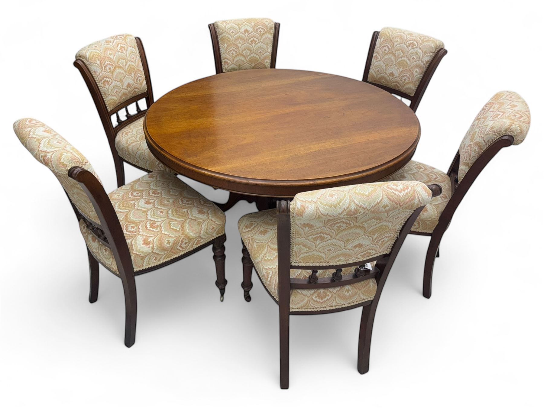 Victorian mahogany centre table, circular top above turned pedestal, terminating on three cabriole legs with scroll feet on porcelain castors, and six scroll carved upholstered dining chairs, with cushion and spindle turned backs, centre table  118x74cm, dining chairs 89x46x50cm