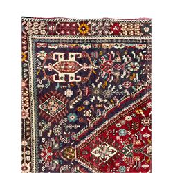 Persian Heriz crimson ground rug, field with large central lozenge surrounded by stylised plant motifs in a mauve background, guarded border with repeating foliage
