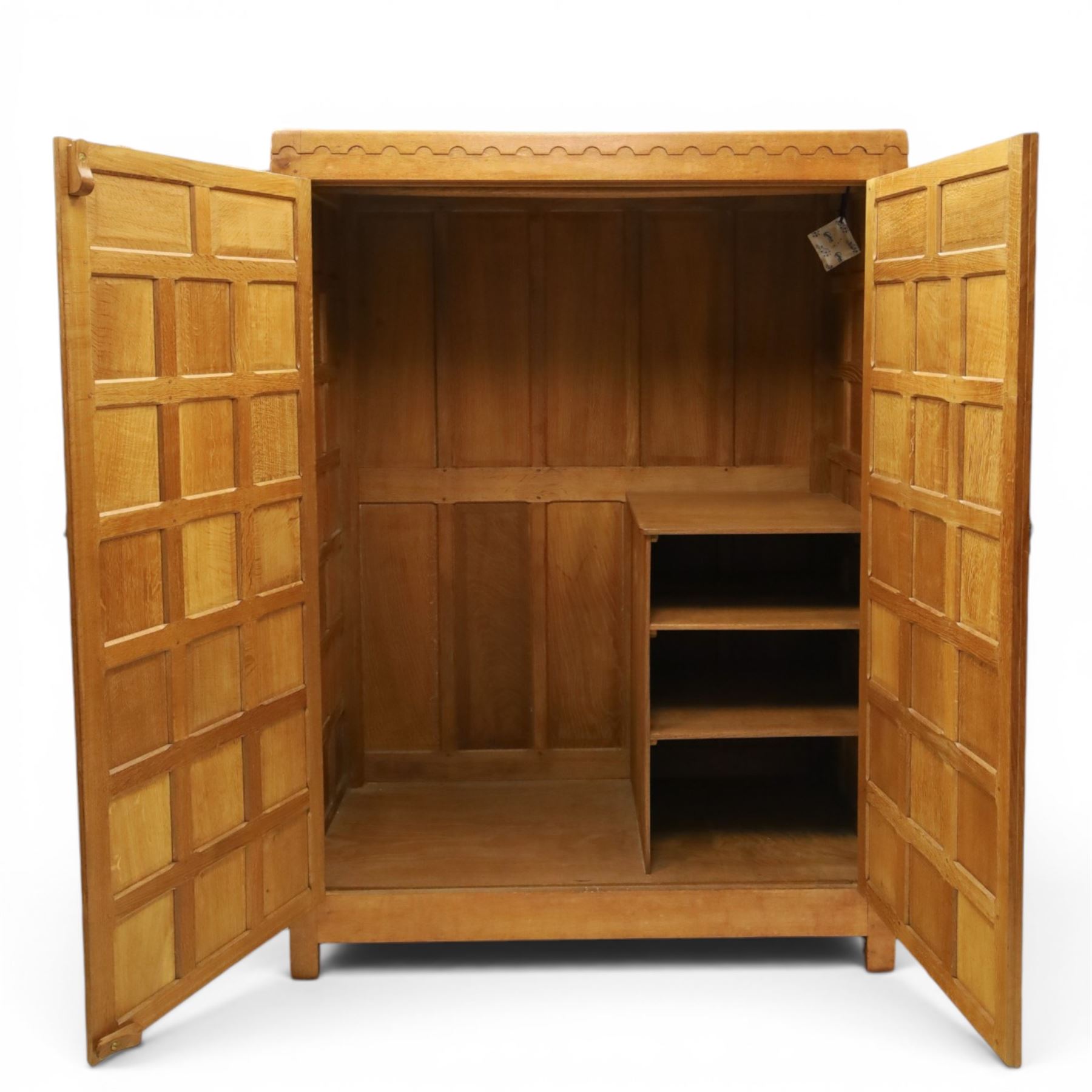 Mouseman - early-to-mid-20th century panelled and adzed double wardrobe, the arcade carved cresting rail over two panelled doors, with wrought metal hinges and latch, deep relief carved mouse signature, the interior fitted with hanging rail, by the workshop of Robert Thompson of Kilburn
