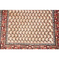Collection of four Persian rugs, comprising a Saraband ivory ground rug with all-over boteh field and multiple borders; a crimson ground Hamadan type rug with all-over stylised floral and geometric motifs; a floral medallion prayer rug with dark field and ivory spandrels; and a Hamadan peach ground rug with repeating stylised flowering plants and dark multiple borders, largest 83cm x 142cm