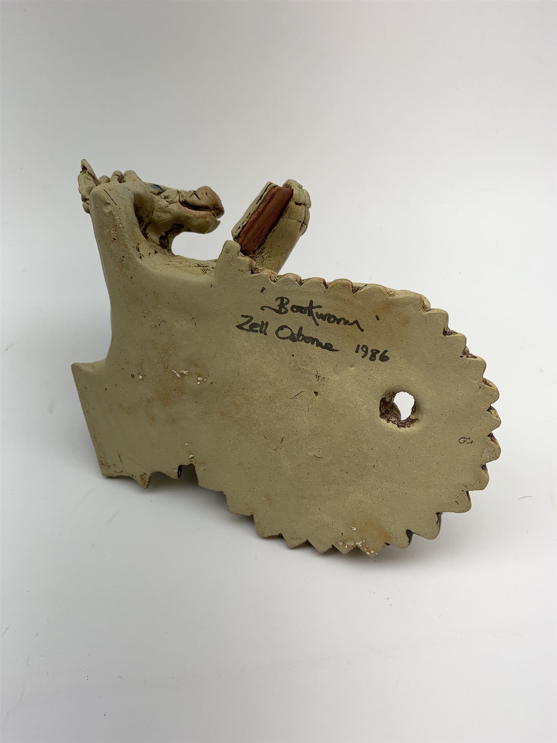 Zell Osbourne (British, Contemporary), Bookworm, a Studio Pottery figure modelled as a recumbent dragon with book, L21cm. 