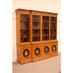 Sheraton Revival satinwood breakfront bookcase, frieze painted with scrolling leafage above four astragal doors with adjustable shelves, the base with four doors painted with floral sprays in oval panels, on a plinth base, W234cm, H235cm, D52cm