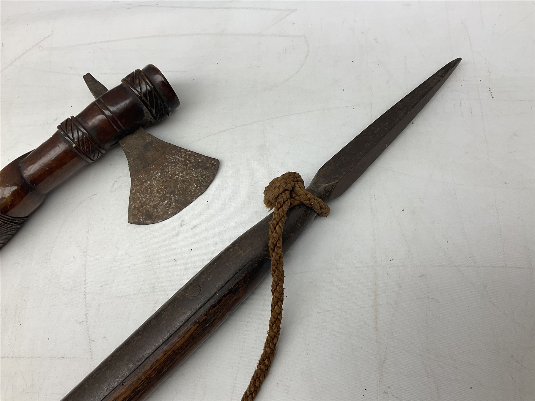 Tribal Art - an African axe, possibly Yoruba, the bone shaft carved as two cord bound stylised figures with iron fan-shaped blade, L35cm overall; and 19th century harpoon or spear head of square section with two long fixing arms on cut-down ash shaft L57cm (2)