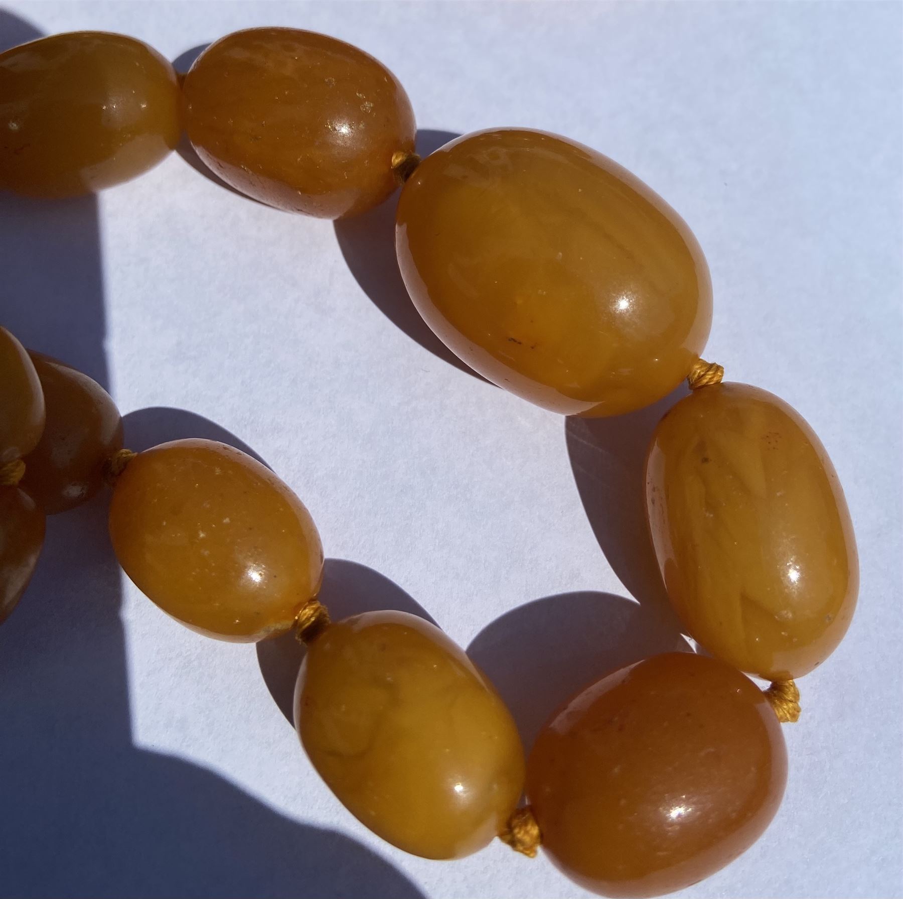 Single strand graduating oval butterscotch amber bead necklace, with three additional loose amber beads