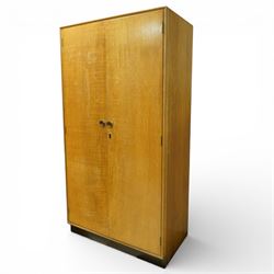 Mid 20th century oak veneered wardrobe, the plain rectangular top above a pair of hinged doors fitted with circular handles, opening to reveal a hanging rail and upper shelf, one door with inset mirror, the whole raised on a plinth base