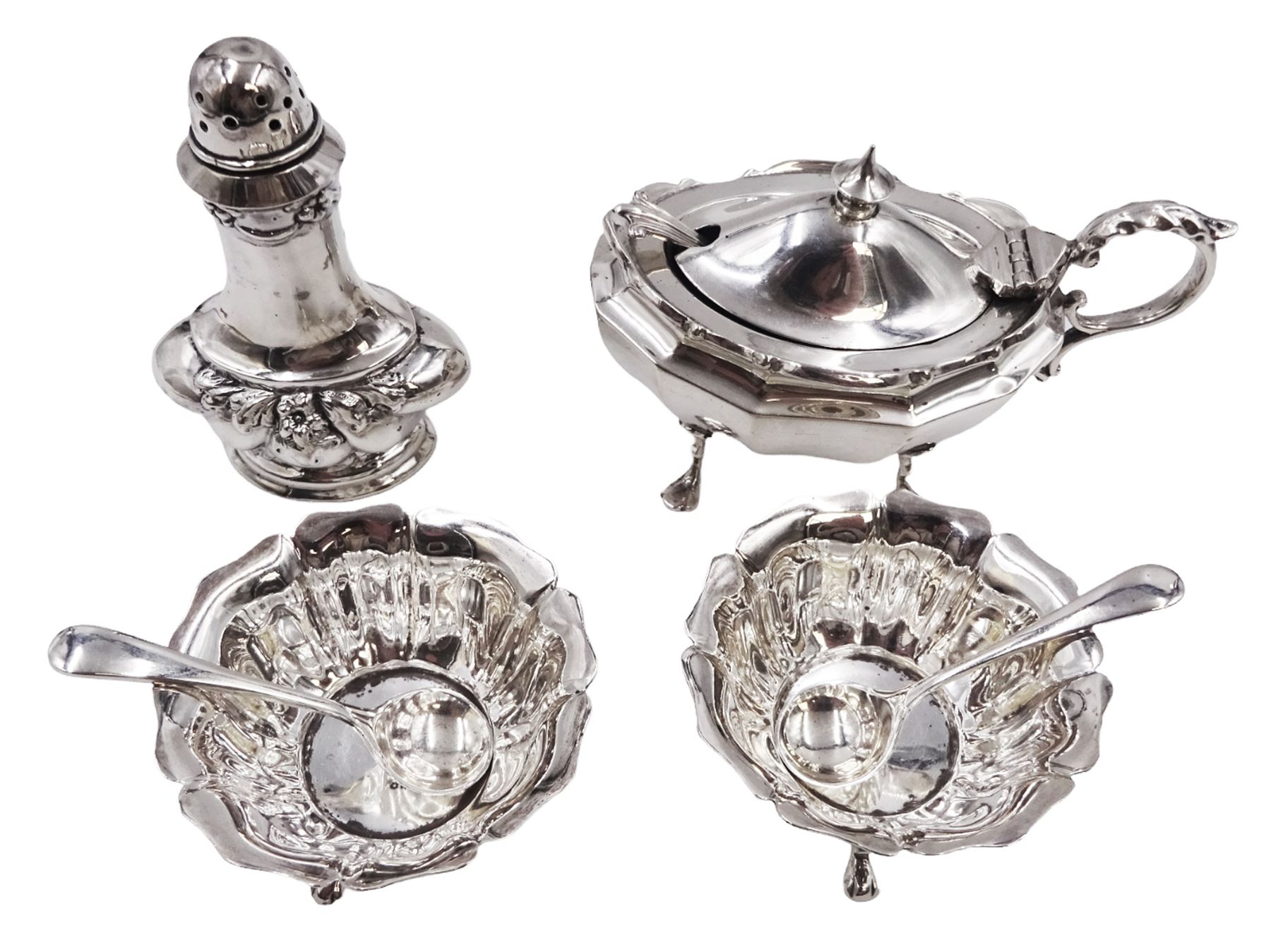 Early 20th century silver mustard pot and cover, of faceted oval form, with shaped rim and acanthus capped scroll handle, upon four pad feet, with matching spoon, H5.5cm, hallmarked I S Greenberg & Co, Birmingham 1912 & 1914, with blue glass liner, together with pair of Victorian silver open salts, of fluted circular form, with lobed rim, upon three pad feet, with matching salt spoons, all hallmarked Atkin Brothers, Sheffield 1899 and a Victorian silver pepper, of waisted baluster form, the part fluted body repousse decorated with flowers and leaves and a floral garland to upper rim, hallmarked William Oliver, Birmingham 1900