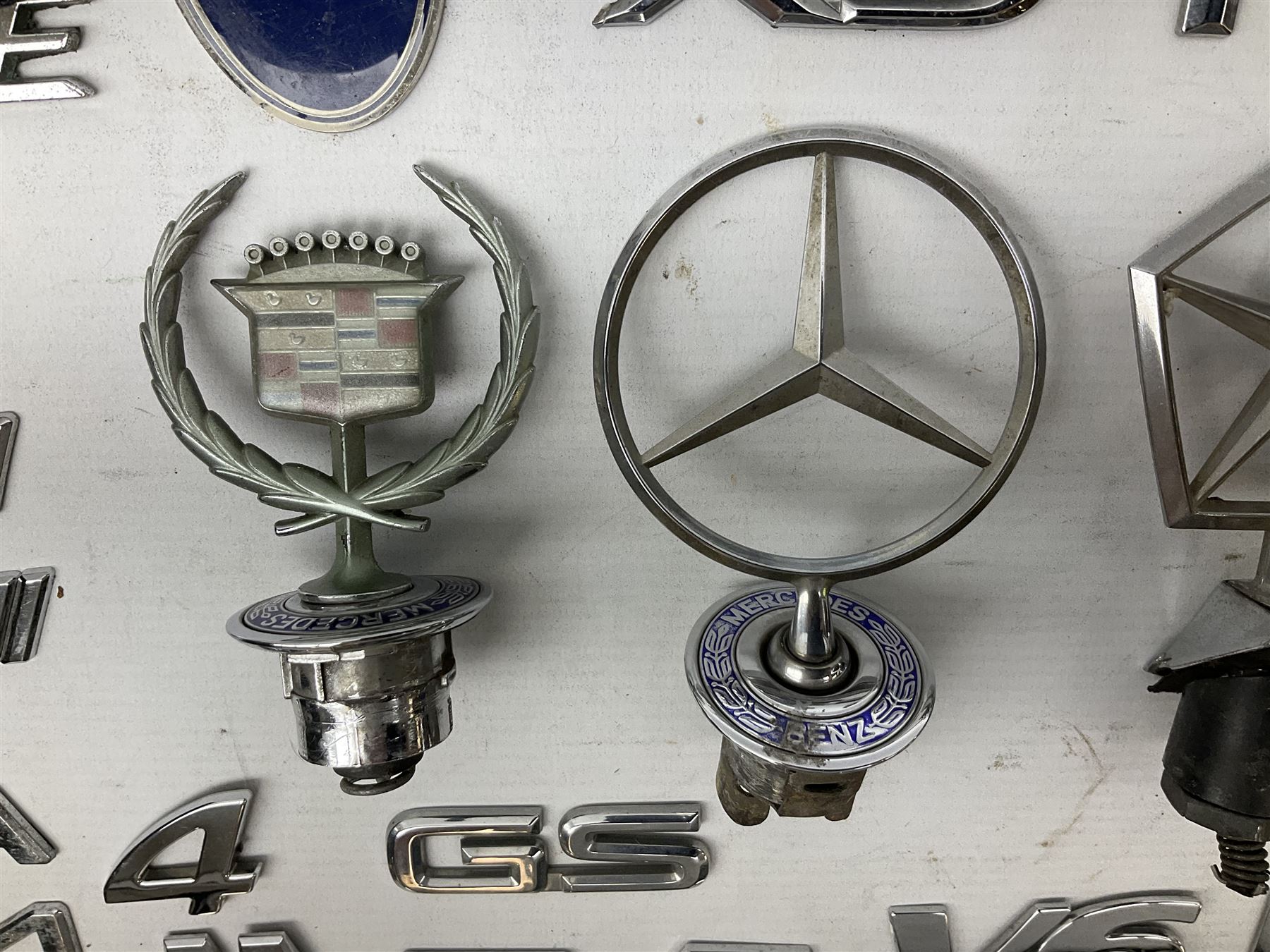 Nickel plated car mascot as a nude lady in a diving pose, similar to an A.E. Lejeune 'Speed Nymph', but marked 'N.L.C. Co. RegEd Des.'; chrome leaping Jaguar car mascot; and quantity of car model name letters, numbers and logos including Mercedes-Benz etc