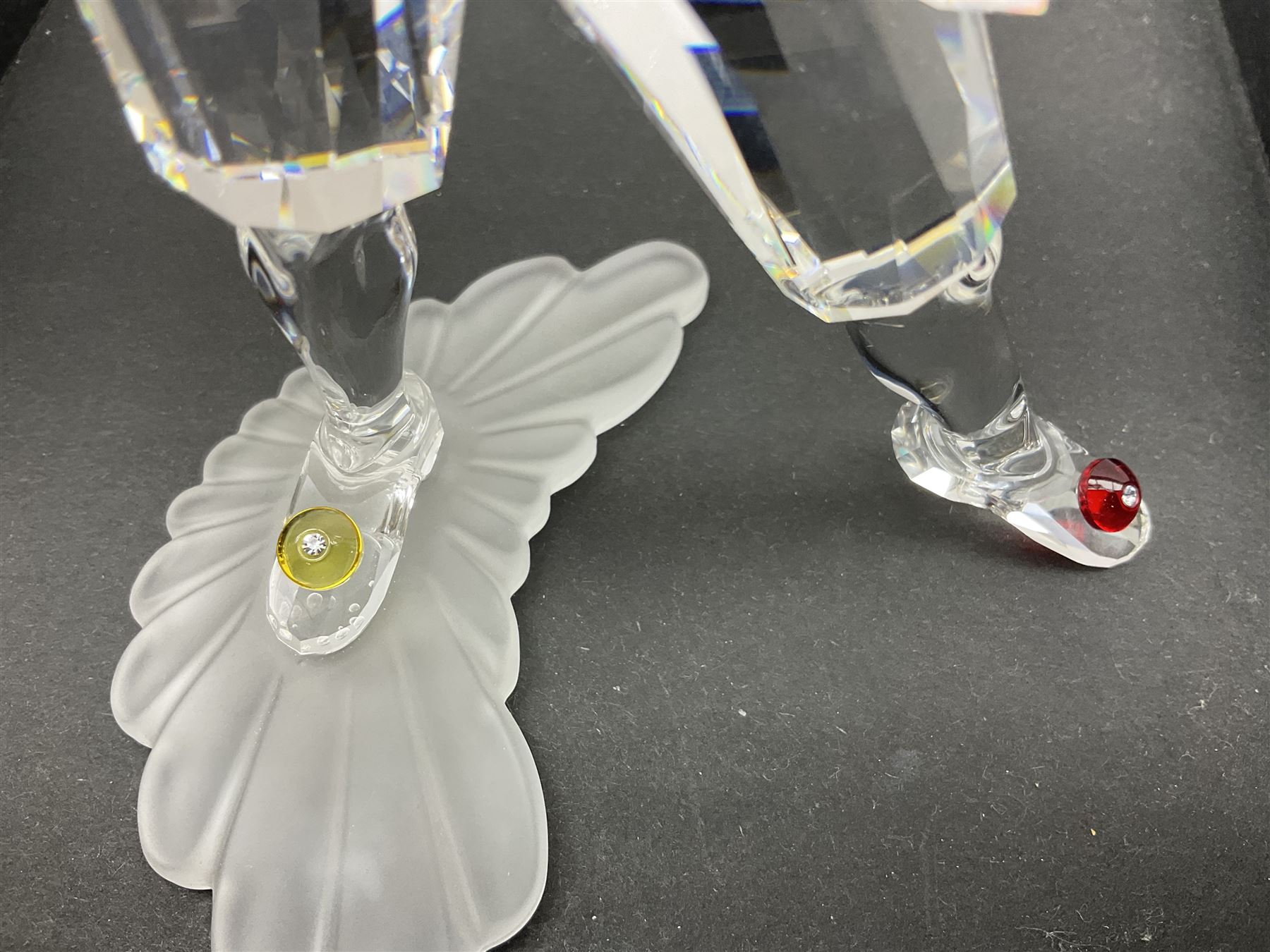 Swarovski Crystal Masquerade trilogy; 1999 Masquerade Pierrot, 2000 Columbine, 2001 Harlequin all with accompanying plaque, stand and original box, together with a glass display case with mirrored back and sides 