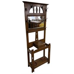 Arts & Crafts period oak hall stand, projecting moulded cornice over arched cut-out decorated with shaped vertical rails, fitted with rectangular bevelled mirror back over hinged glove compartment, on straight pierced supports with shaped pediments 